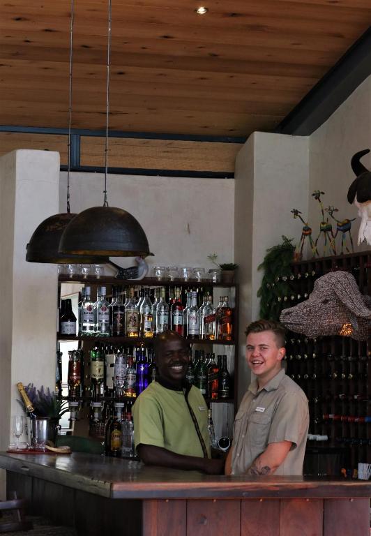 two men are standing at a bar at Greenfire Game Lodge in Balule Game Reserve