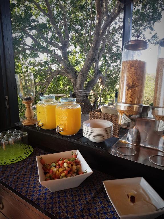a table with a bowl of fruit and glasses of orange juice at Greenfire Game Lodge in Balule Game Reserve