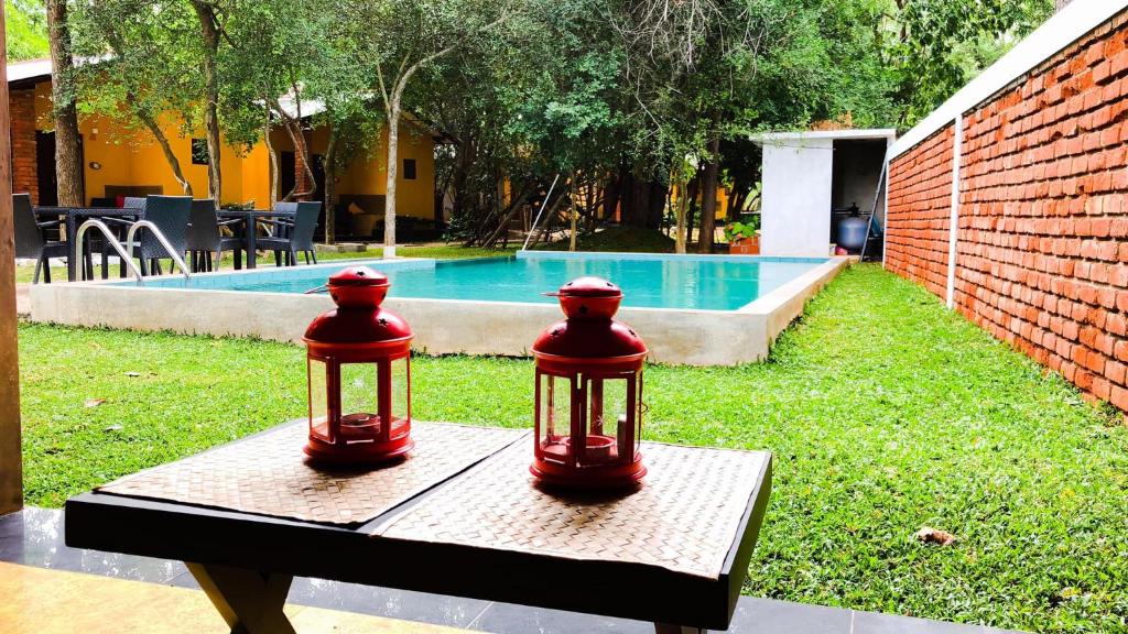 dos linternas rojas sentadas en una mesa junto a una piscina en Sigiri Resort, en Sigiriya