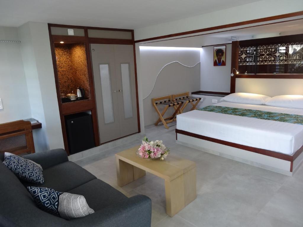 una camera con un grande letto e un divano di Pension Tiputa Lodge Rangiroa a Tiputa
