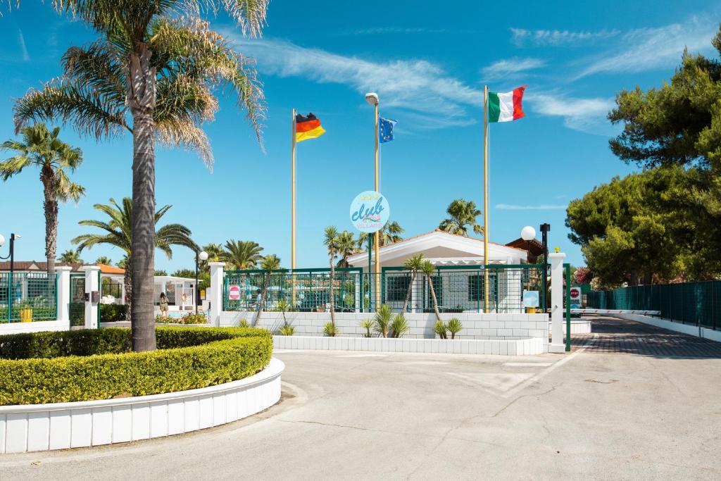 un parque con banderas frente a un edificio en Villaggio Club In en Vieste