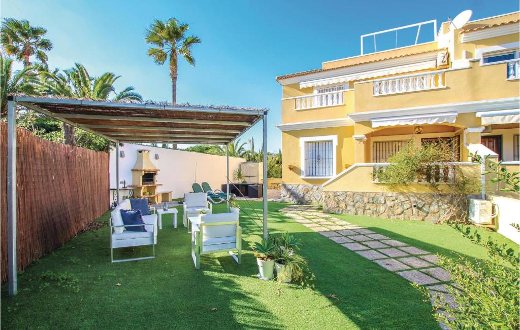 オリフエラ・コスタにあるBeautiful Home In Orihuela Costa With 3 Bedroomsの裏庭(芝生の上に椅子とパーゴラ付)