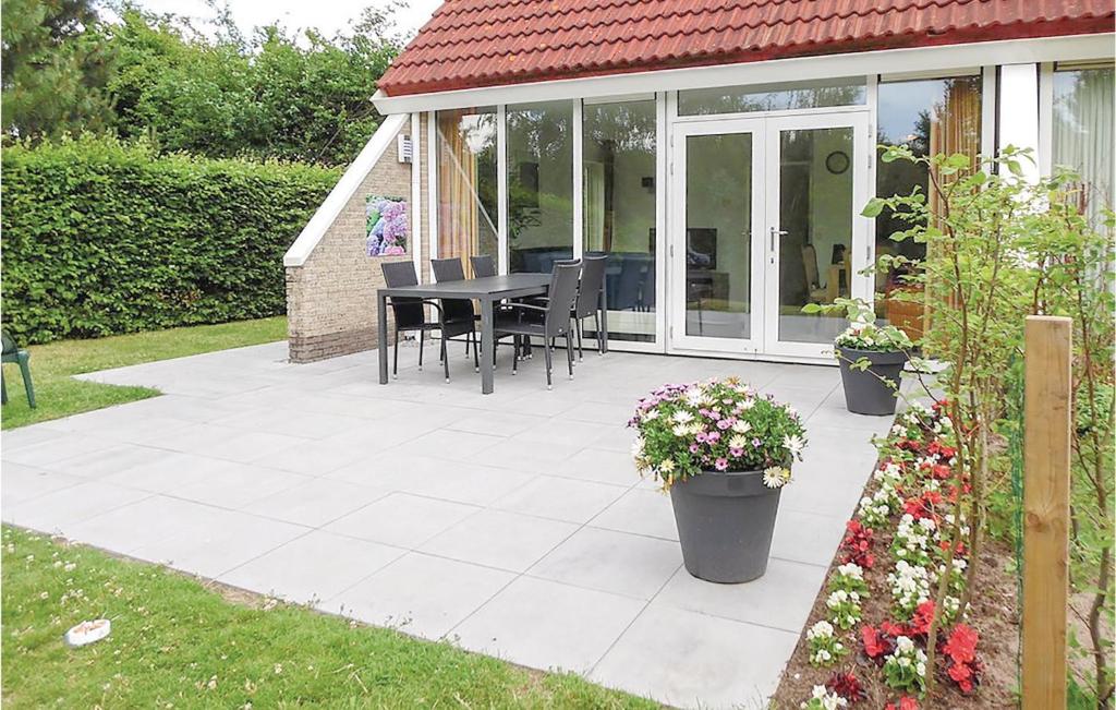 un patio con mesa, sillas y flores en Pet Friendly Home In Vlagtwedde With Wifi, en Vlagtwedde