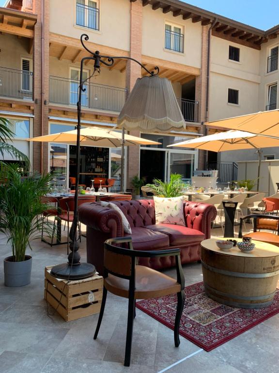 un patio con sofá, mesas y sombrillas en HILL COLLE - camere & bistrot, en Villa Pedergnano