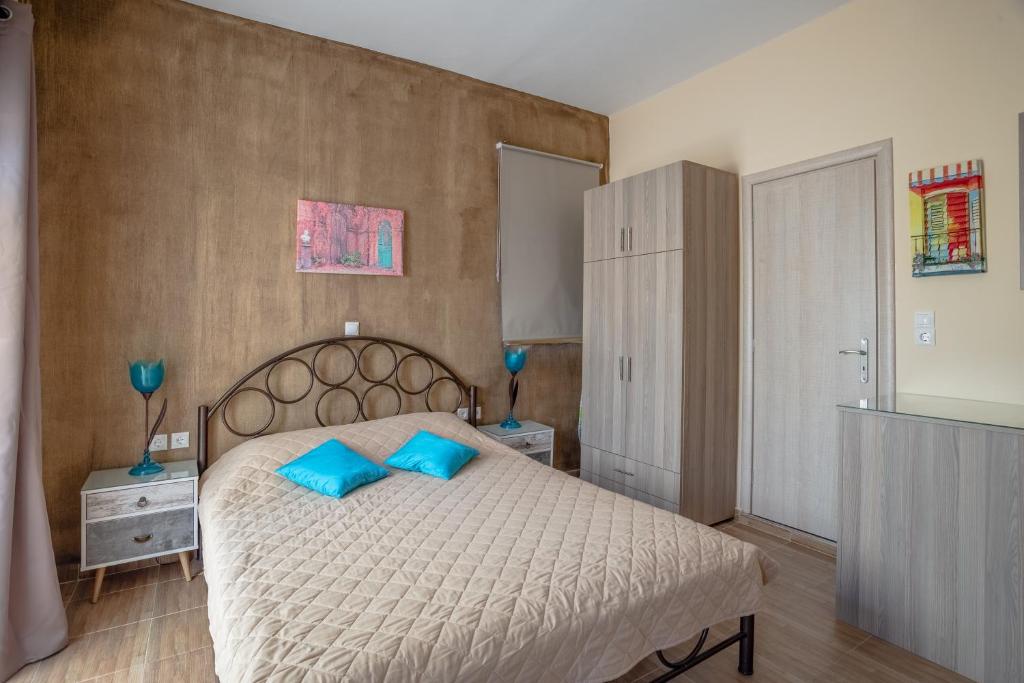 a bedroom with a large bed with blue pillows at Cosy studio 1 in Stoupa in Stoupa