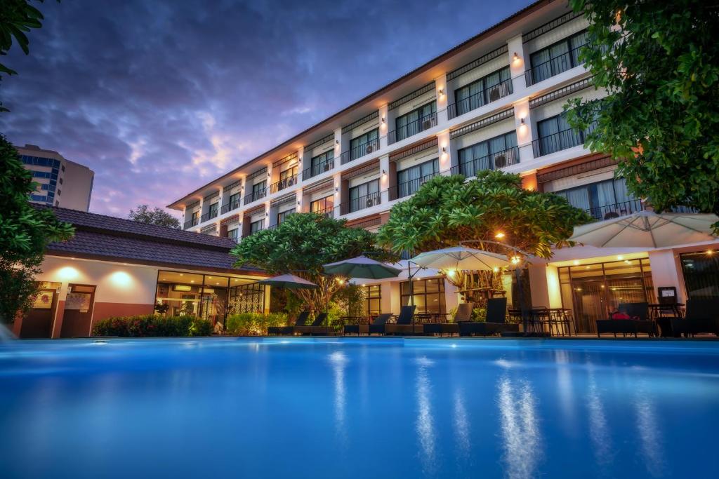 a hotel with a swimming pool in front of a building at The Pannarai Hotel in Udon Thani