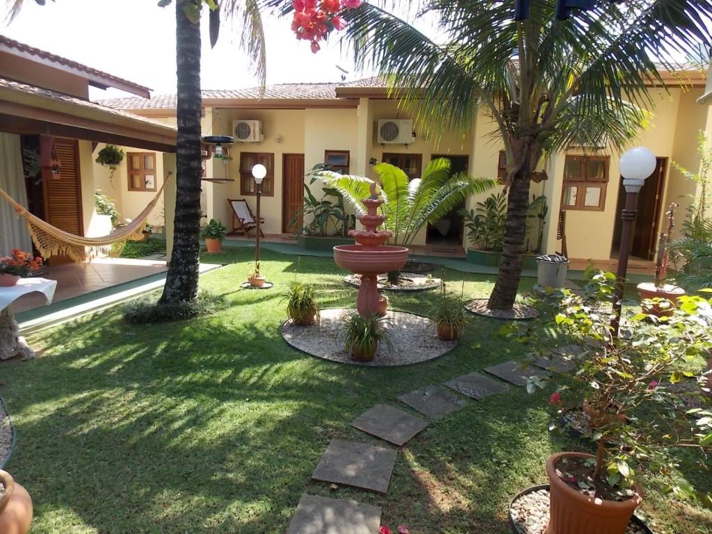 a courtyard with palm trees and a fountain at Suítes Jardim dos Sonhos in Ubatuba