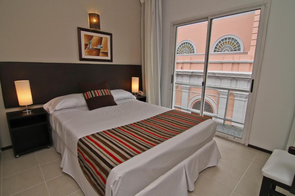1 dormitorio con cama grande y ventana grande en De la Plaza Hotel, en Maldonado