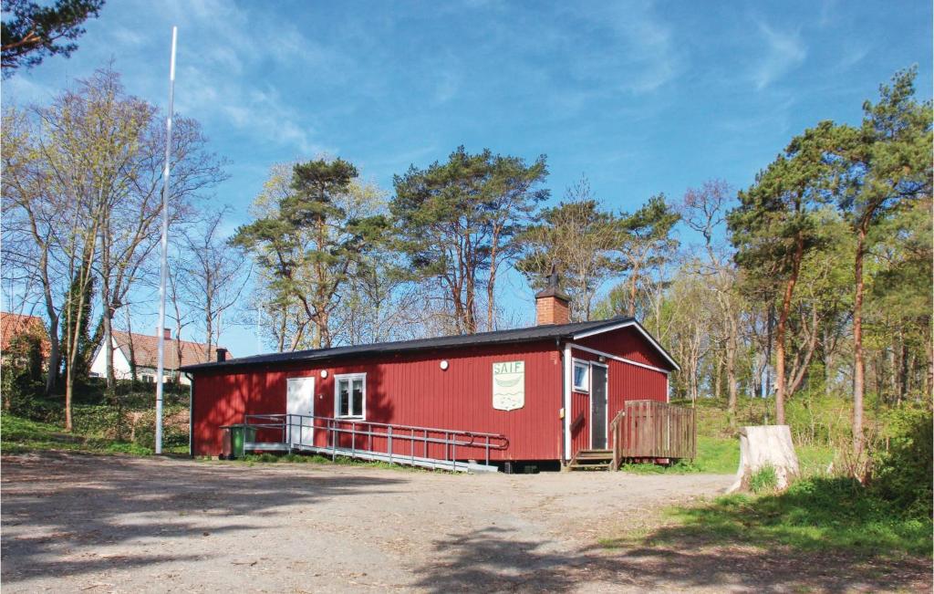 a red shed with a black roof in a field at Stunning Home In Simrishamn With Kitchen in Simrishamn