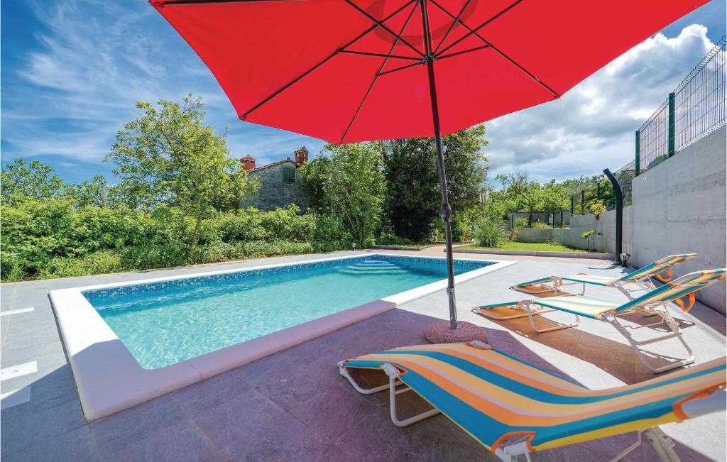 een zwembad met 2 stoelen en een rode parasol bij Beautiful Home In Labin With Kitchen in Labin