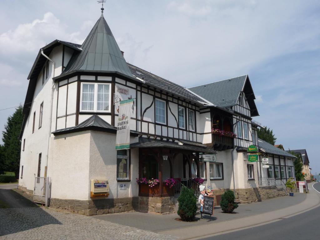 ein schwarzweißes Gebäude an der Ecke einer Straße in der Unterkunft Hotel Güldene Gabel in Unterwellenborn