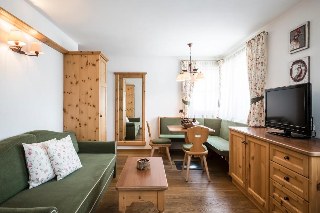 a living room with a green couch and a tv at Piculin Alpin Apartments in San Martino in Badia
