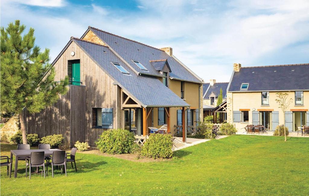 une maison avec une table et des chaises dans la cour dans l'établissement Les Hauts De La Houle, à Cancale