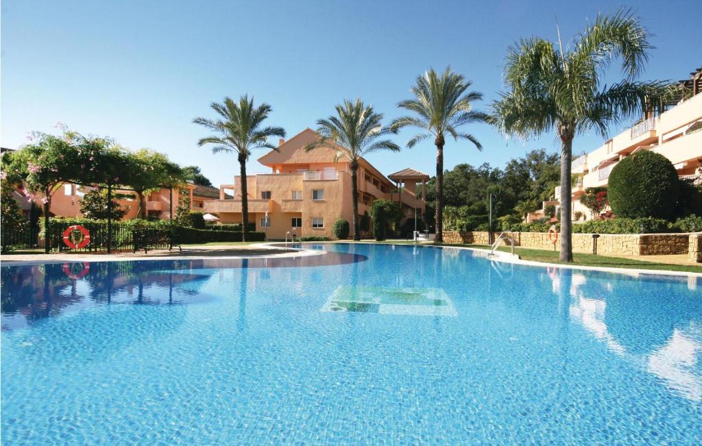 マルベーリャにあるNice Apartment In Marbella-elviria With Wifi, Outdoor Swimming Pool And Swimming Poolのヤシの木や建物のある大型スイミングプール