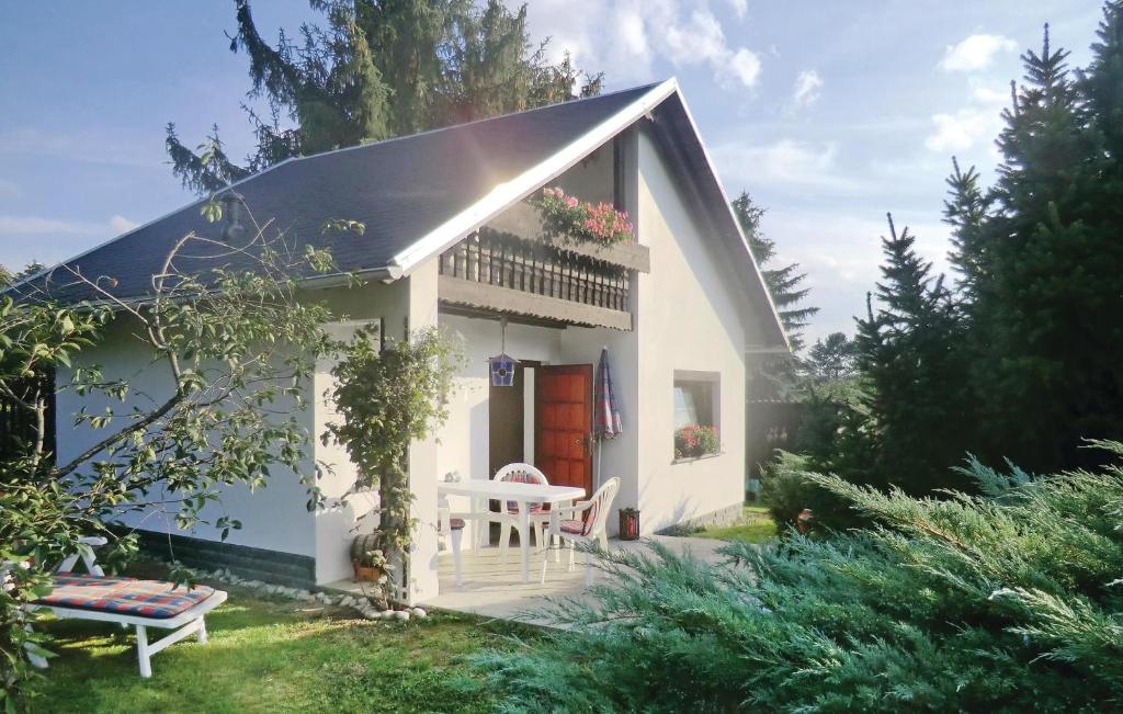ein kleines weißes Haus mit einer Bank im Hof in der Unterkunft Ferienhaus Thiergartener Str. T in Taltitz