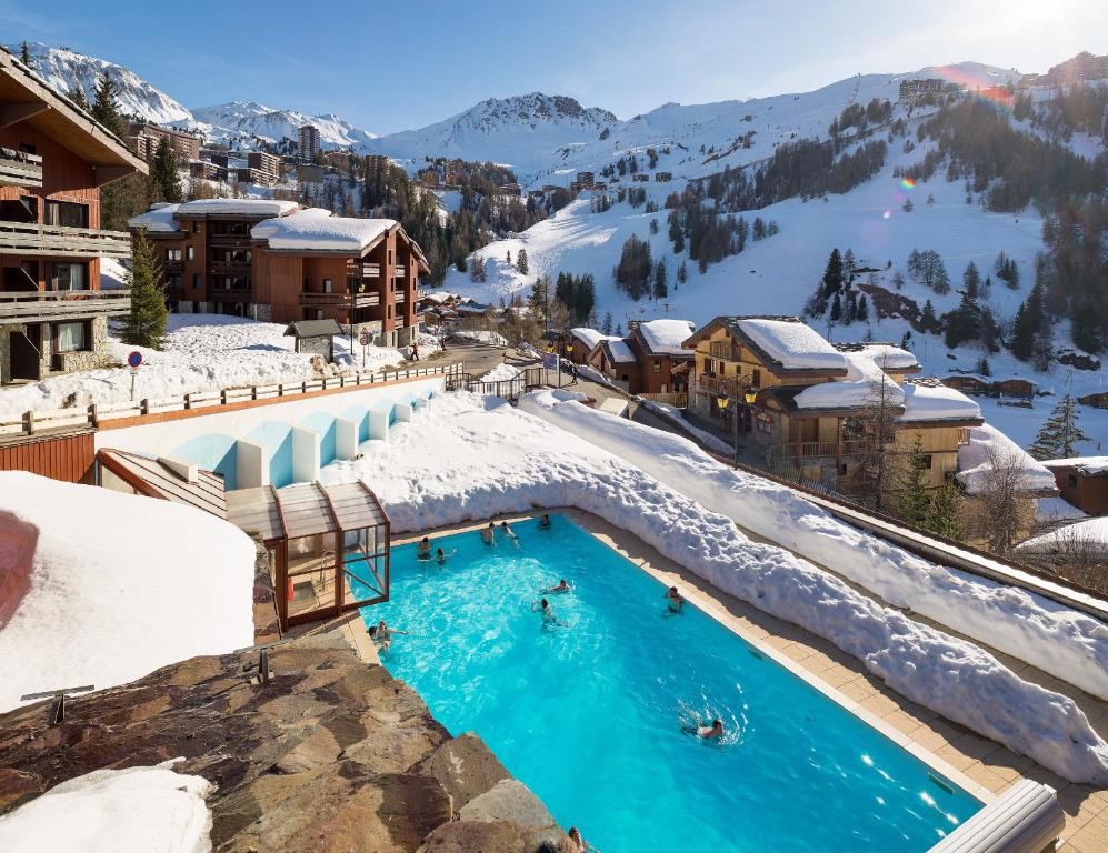 a resort with a swimming pool in the snow at Residence Plagne Lauze - maeva Home in Plagne 1800