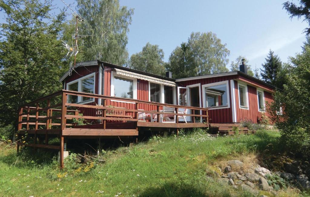 a red cabin with a deck in a field at Beautiful Home In Ljungbyhed With Sauna in Röstånga