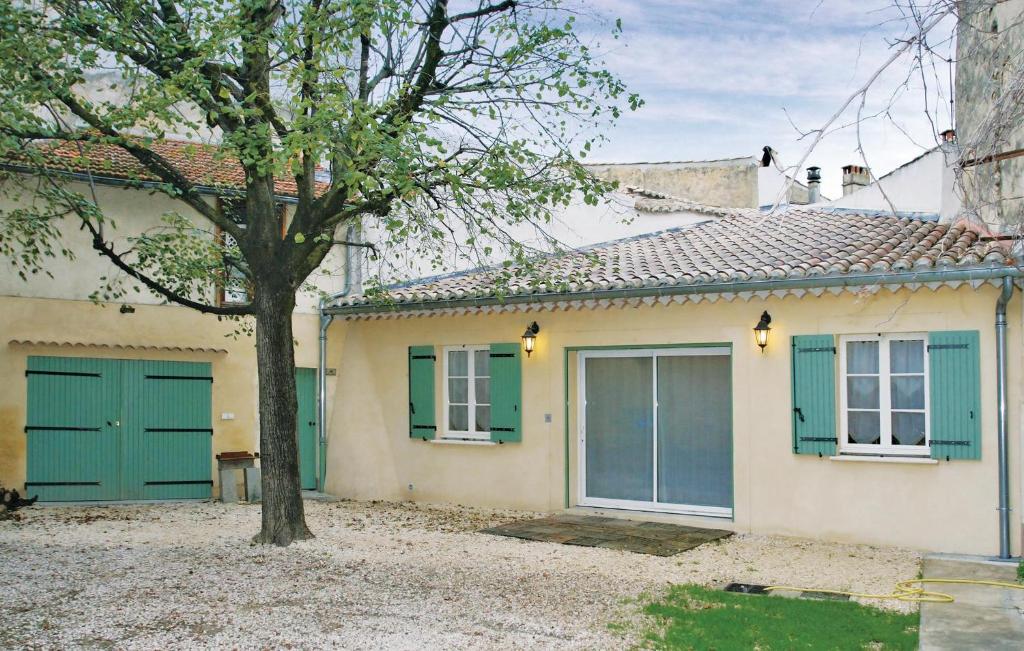 a house with green doors and a tree at Holiday Home Rue De L`escuraille in Suze-la-Rousse
