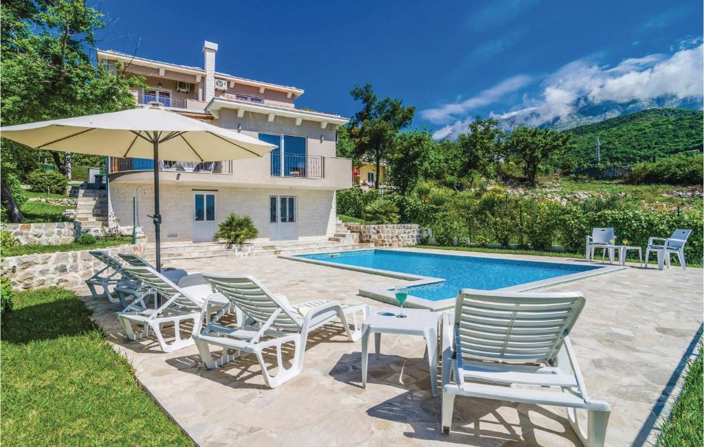 a group of chairs and an umbrella next to a swimming pool at Cozy Home In Igalo With Wifi in Herceg-Novi