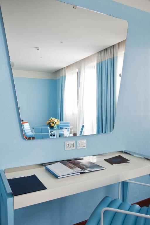 a dressing table with a mirror on a blue wall at JR Hotels Bari Grande Albergo delle Nazioni in Bari