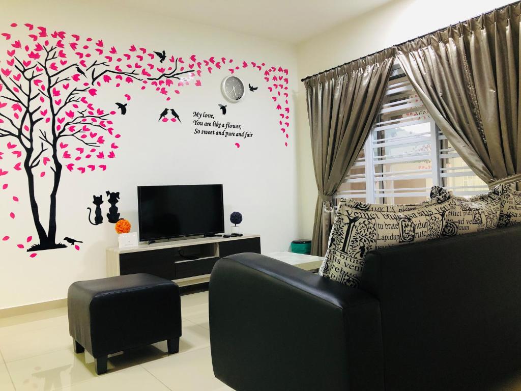 a living room with a couch and a tv and a tree at De Little Cabin - 7mins to Sunway Iost World of Tambun in Ipoh
