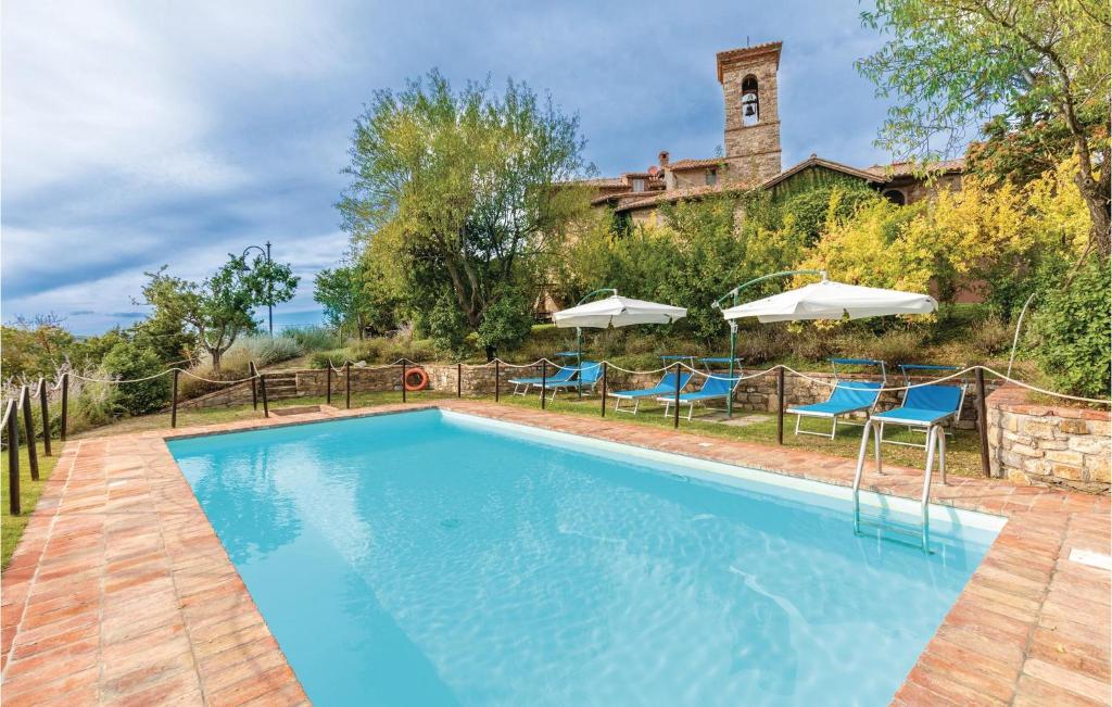 a swimming pool with blue chairs and umbrellas at La Canonica in Piegaro