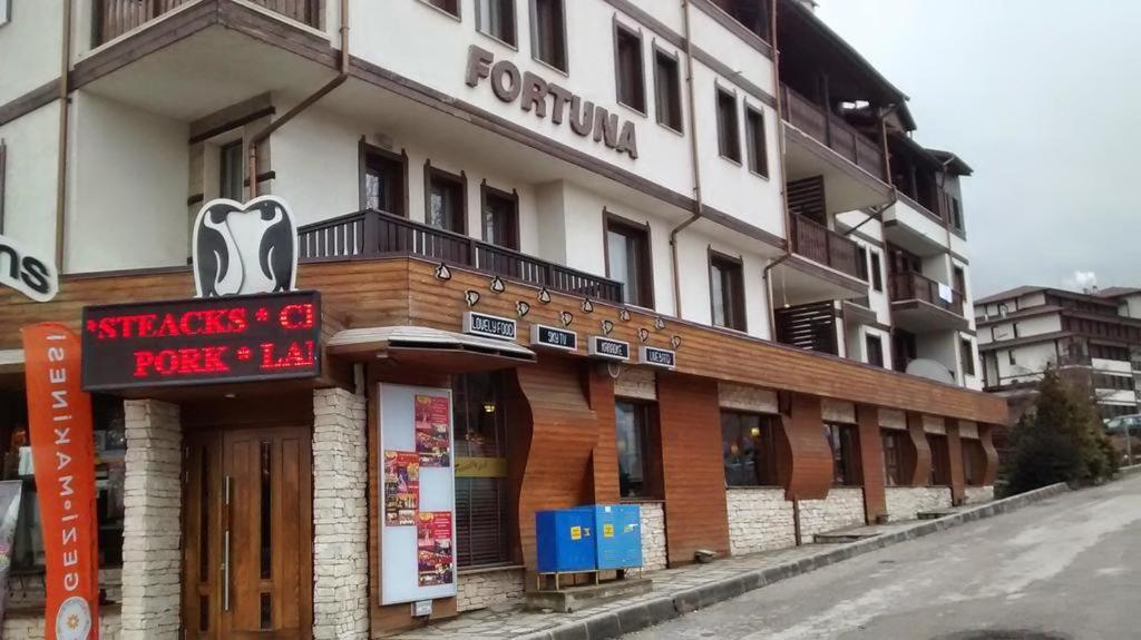 un edificio con una señal delante de él en Fortuna Apartments, en Bansko