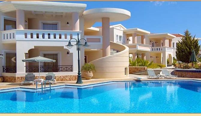 a large house with a swimming pool in front of it at Sissy Village All Suite Hotel in Kounoupidhianá