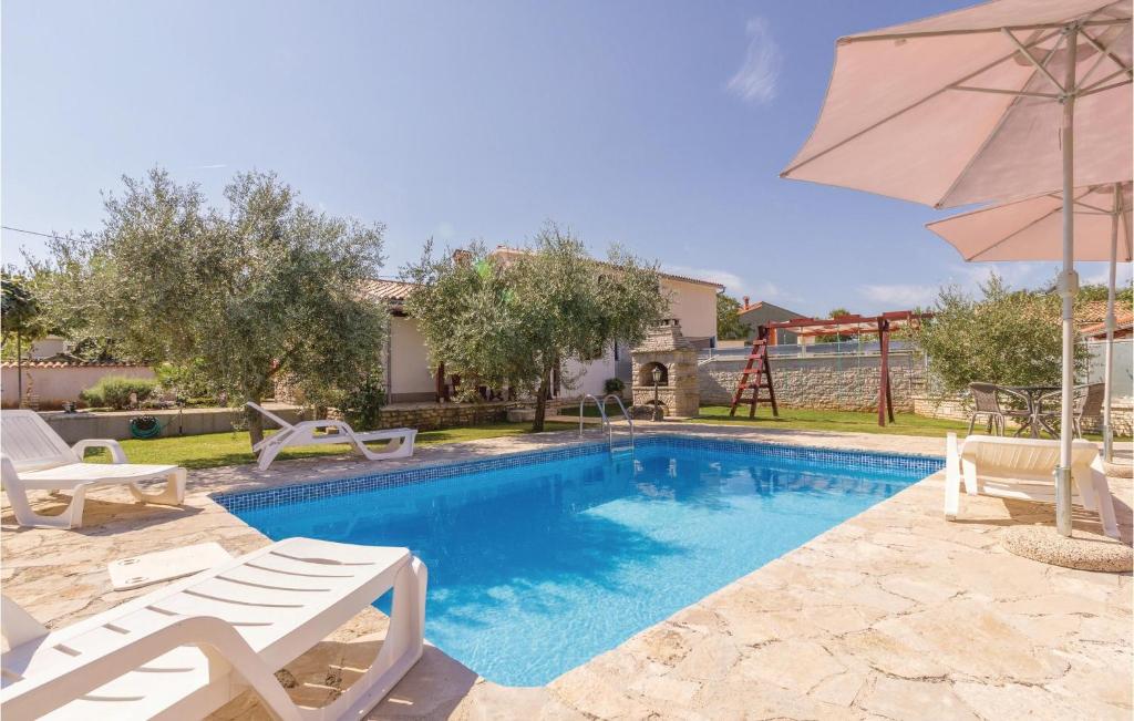 a swimming pool with two chairs and an umbrella at 2 Bedroom Beautiful Home In Rebici in Rebići