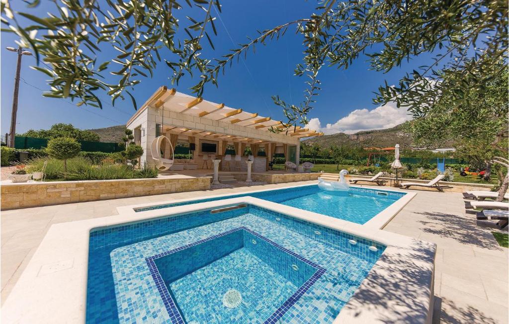 a swimming pool in front of a house at Beautiful Home In Seget Donji With Heated Swimming Pool in Trogir