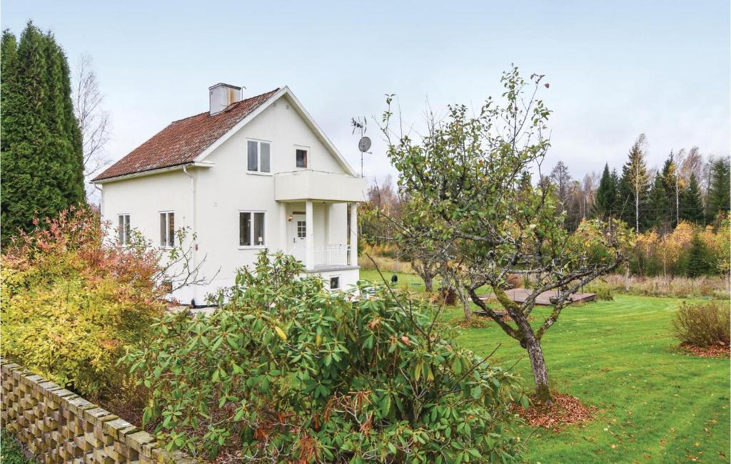 a white house in a yard with a tree at Cozy Home In sensbruk With Kitchen in Åsensbruk