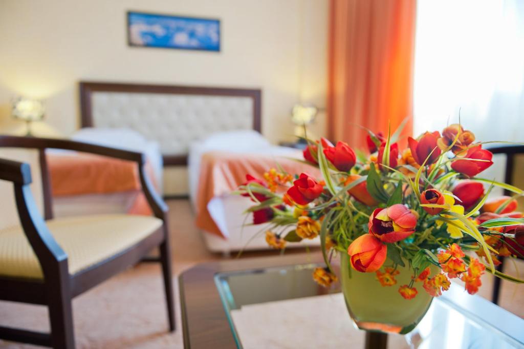 a vase with flowers on a table in a room at Voronezh Hotel in Voronezh