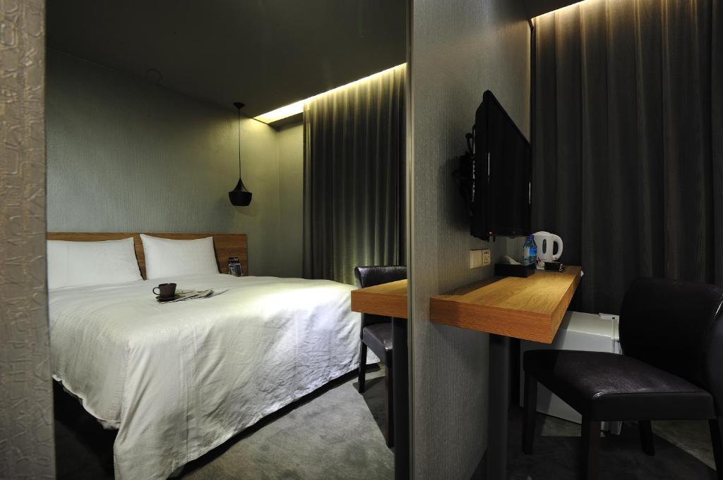 Habitación de hotel con cama, escritorio y TV. en Forward Suites II, en Taipéi