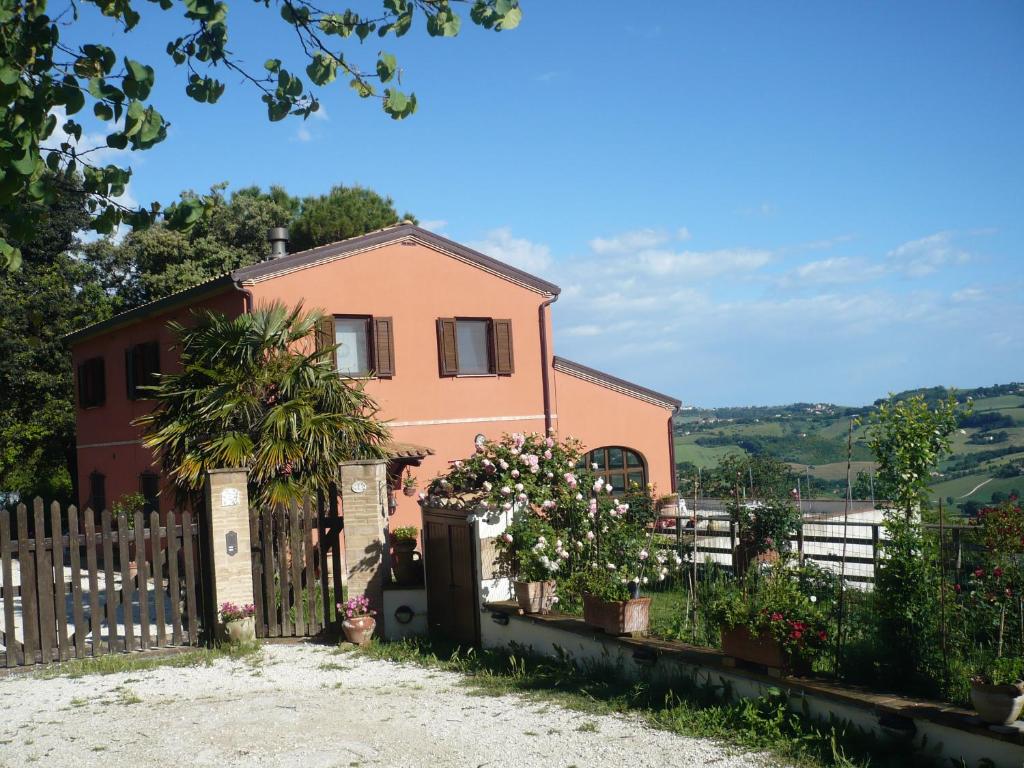 a pink house with a fence and flowers at B&B Punto Magico in Offagna