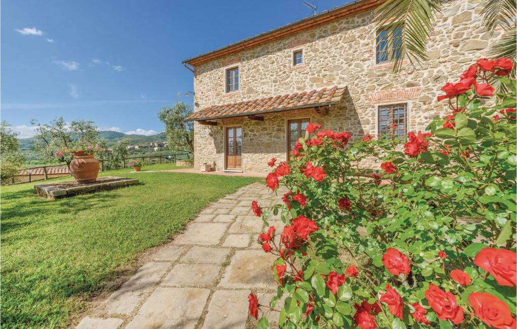 a stone house with red roses in the yard at Leccino in Lamporecchio