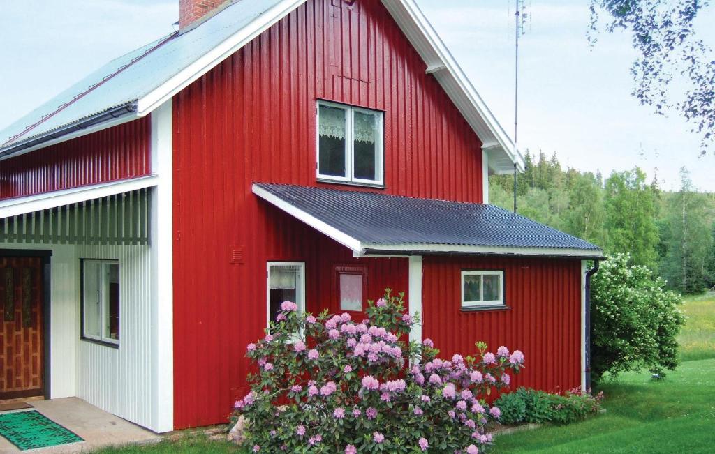 ein rotes Haus mit Blumen davor in der Unterkunft Beautiful Home In Tcksfors With 2 Bedrooms in Navarsviken