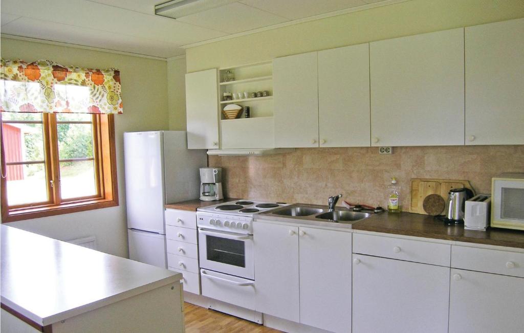 a kitchen with white cabinets and a white stove top oven at Awesome Home In Broaryd With 2 Bedrooms in Bohult