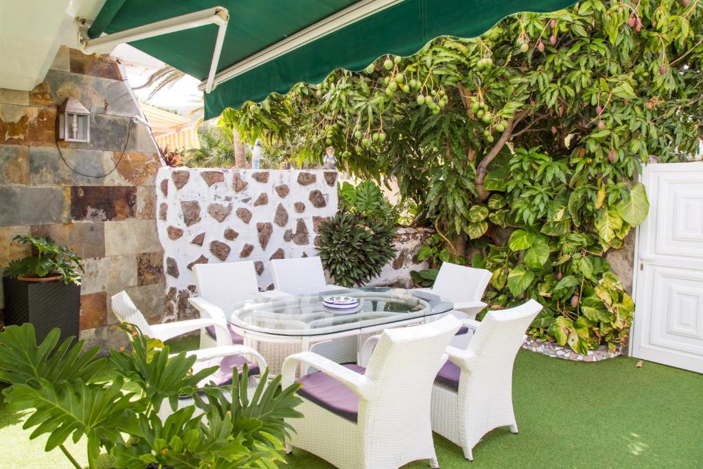 eine Terrasse mit einem Tisch, weißen Stühlen und Pflanzen in der Unterkunft San Juan Beach in Puerto Rico de Gran Canaria