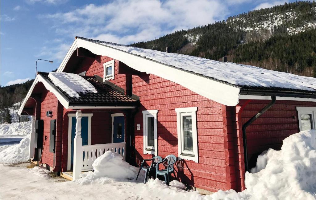 une maison rouge dans la neige avec deux chaises dans l'établissement Awesome Home In Brans With Wifi, à Branäs