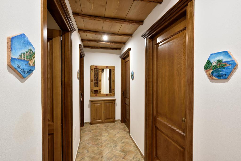 a corridor of a hallway with a door and paintings on the walls at Hotel Goloritzé in Baunei