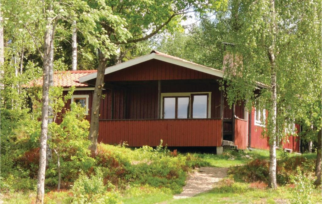 a red cabin in the woods with trees at Pet Friendly Home In Simlångsdalen in Älmhult