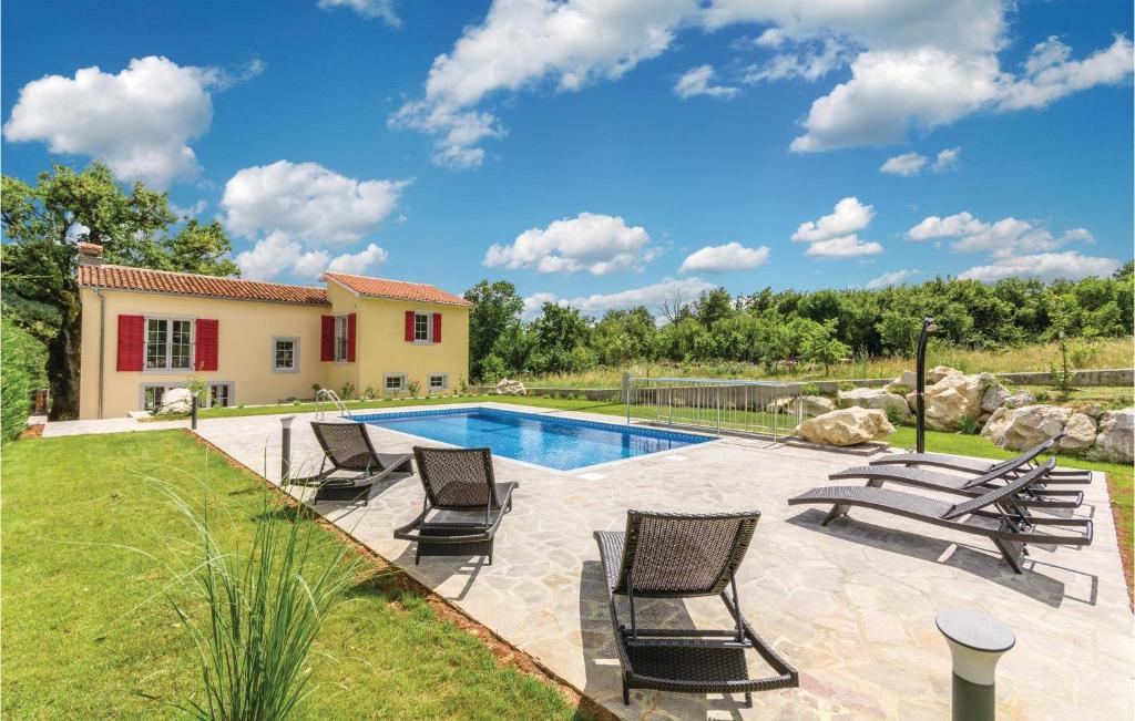 a swimming pool with chairs and a house at Gorgeous Home In Lupoglav With Kitchen in Lupoglav