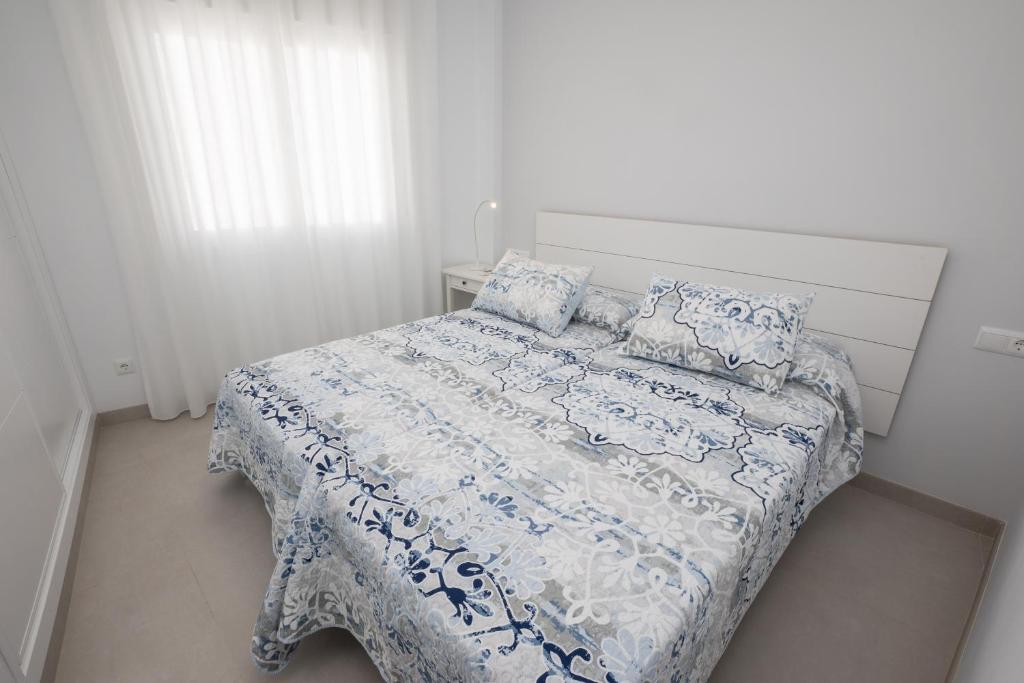 Schlafzimmer mit einem Bett mit einer blauen und weißen Bettdecke in der Unterkunft Apartamentos Mombasa 2 planta in Nerja