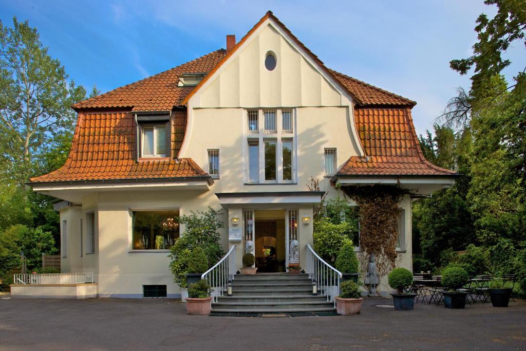 ein weißes Haus mit orangefarbenem Dach in der Unterkunft Hotel Villa Meererbusch in Meerbusch