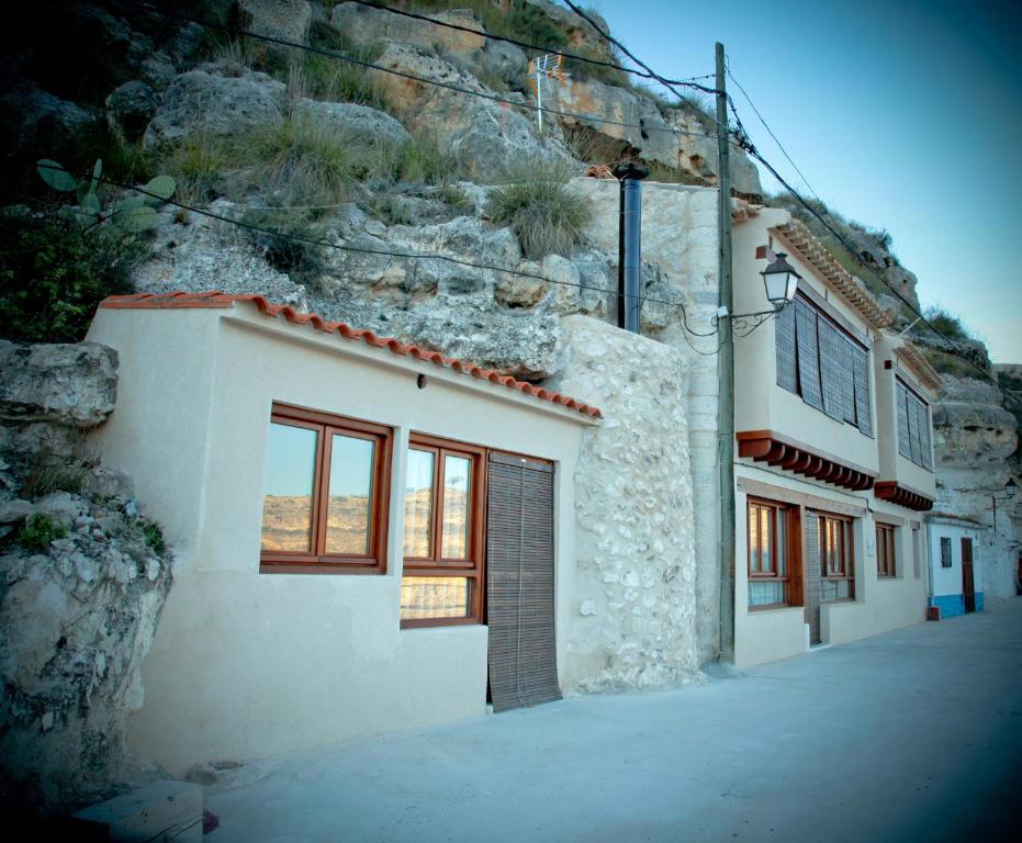 a white building with windows and a mountain at Casa Rural La Bodeguilla in Alcalá del Júcar