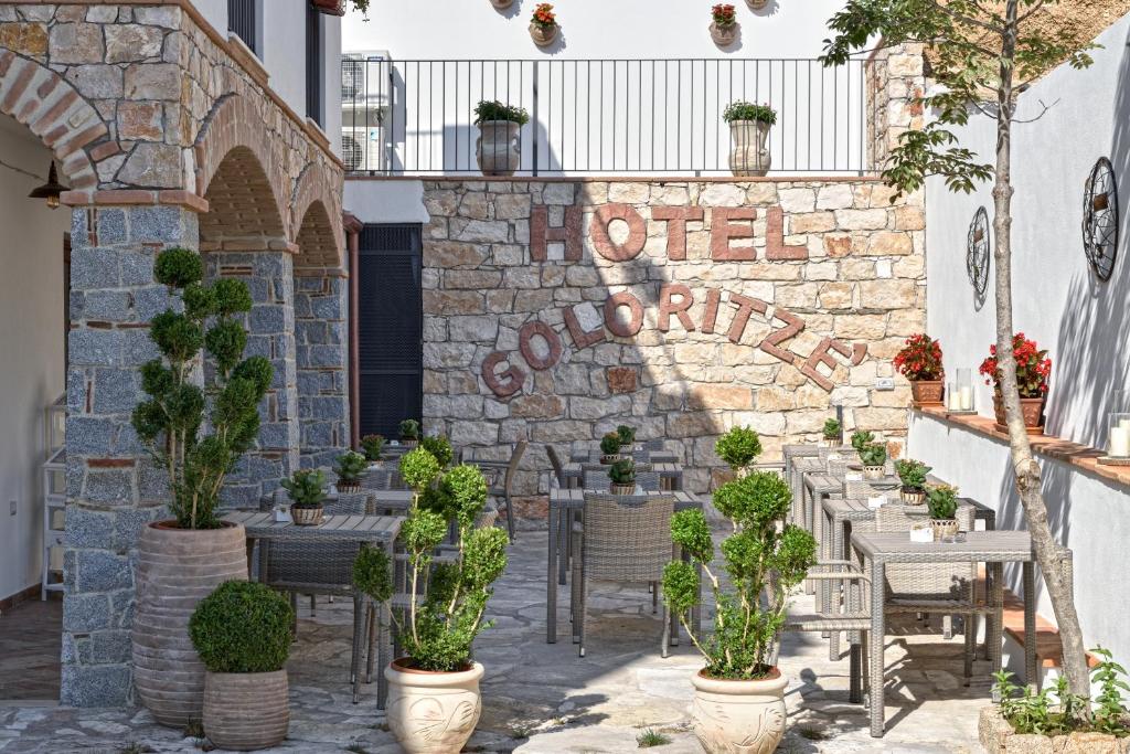 un muro in pietra con tavoli, sedie e piante di Hotel Goloritzé a Baunei