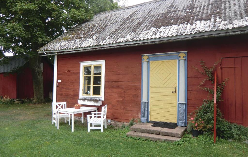 a red house with a yellow door and a table and chairs at Stunning Home In Borgholm With Kitchen in Borgholm