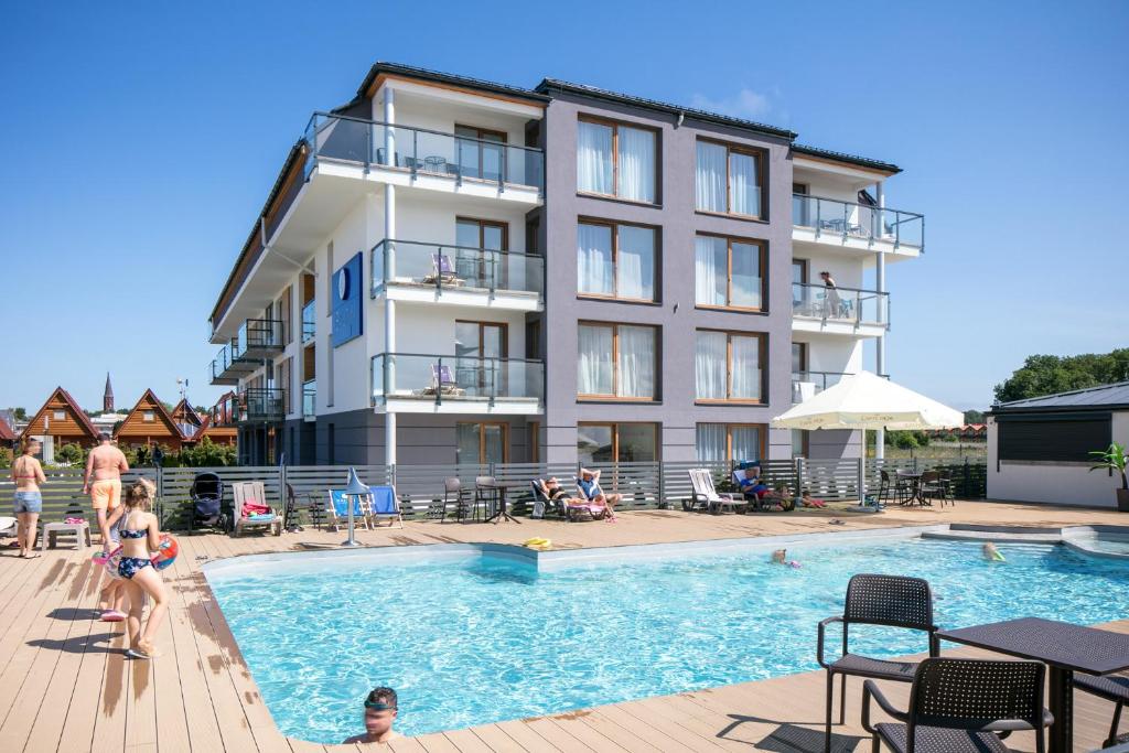 a hotel with a swimming pool in front of a building at Blu Apartments in Sarbinowo