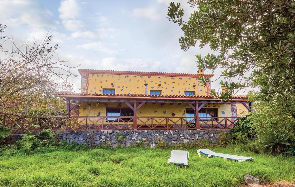 Stunning Home In Icod El Alto With House A Mountain View في Icod el Alto: منزل أصفر بجدار حجري في حقل