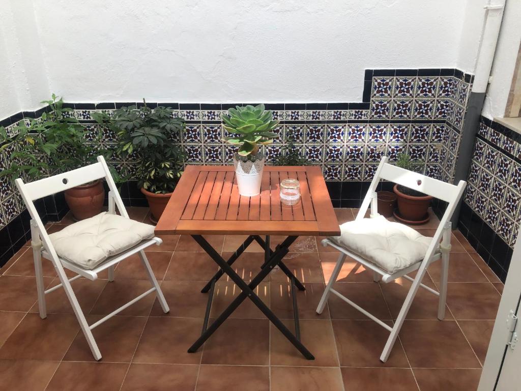 een houten tafel met twee stoelen en een tafel met een plant bij Piso Turistico/Vacacional LM in Ronda